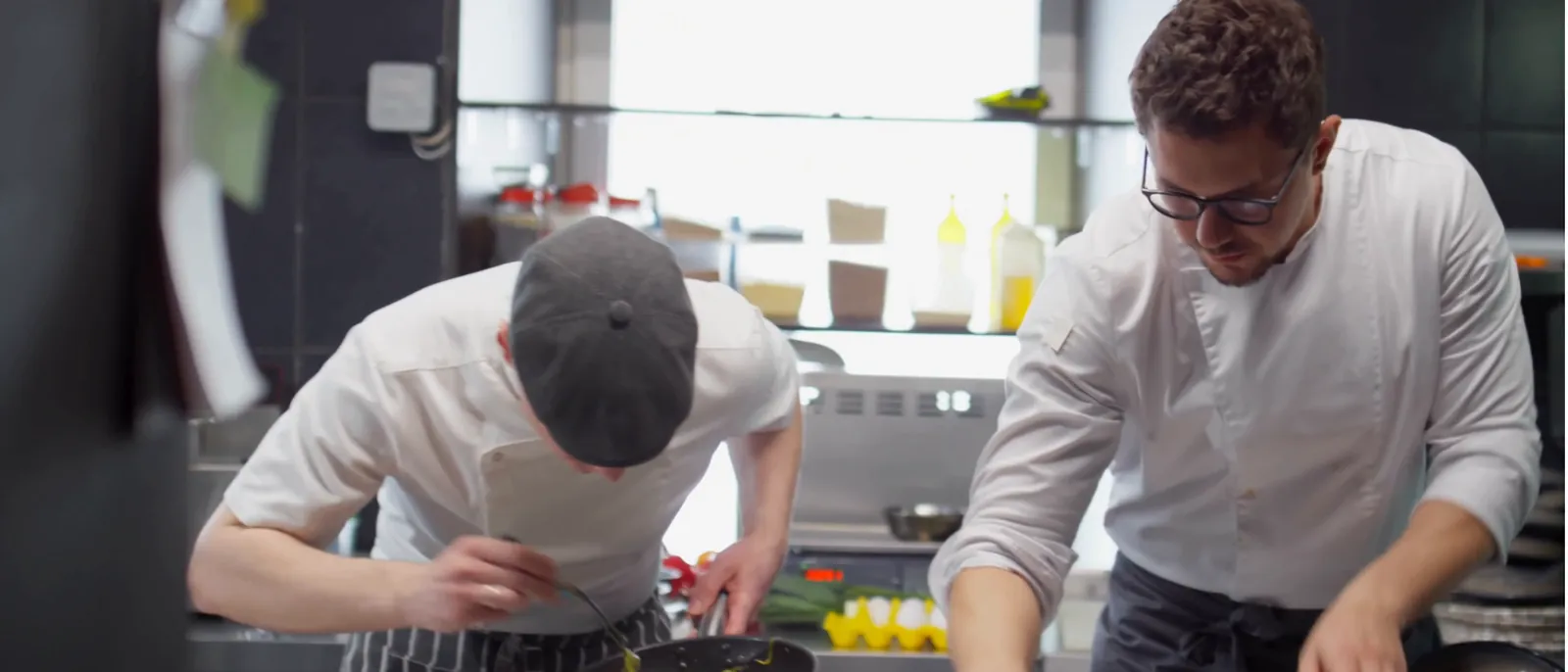 Chefs working the line during service in a bright restaurant kitchen