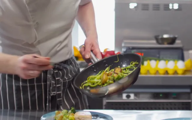 Chef finishing a pan of vegetables during service